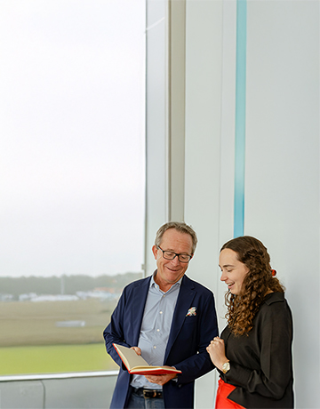2 collega’s die met elkaar praten en in een boek kijken