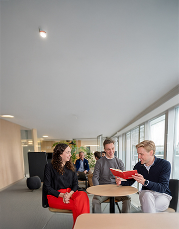 Mensen in gesprek terwijl men een boek bekijkt.